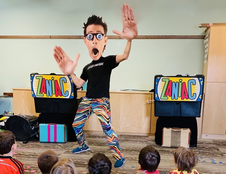 Alex Zerbe transforms into a life-sized dancing bobblehead, triggering laughter and squeals from his young audience.
