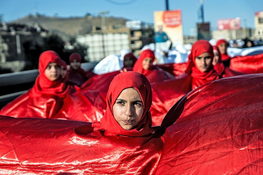 As part of a massive display of the Yemeni flag colors, young women prepare to parade on the second anniversary of Yemen’s Youth Revolution Feb. 11, 2013.