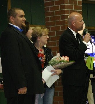 Peninsula High School senior James Washington gives  a bouquet of flowers to his mentor, Donna Forbes, as  auctioneer Jim Borgen tells the audience that attendance  was more than double the original estimate and that the  hoped for proceeds of $5,000 had been substantially  exceeded. Photo by Hugh McMillan