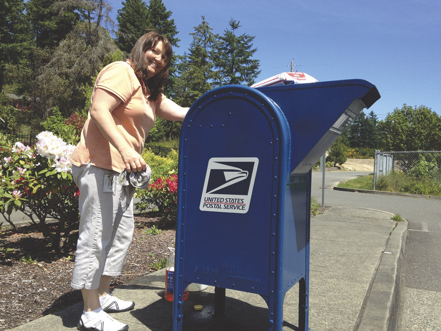 Vaughn Postmaster DeeDee Emmett catches up on some spring-cleaning outside her office in early June. “I came out to put a new sticker on the box and realized it was filthy,” she said. “And, it’s a sunny day, so…” Photo: Ted Olinger, KP News