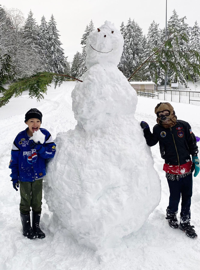 Giant snowman created by Aaron Baldwin, flanked by Roman Baldwin (left) and Josiah Baldwin (right).