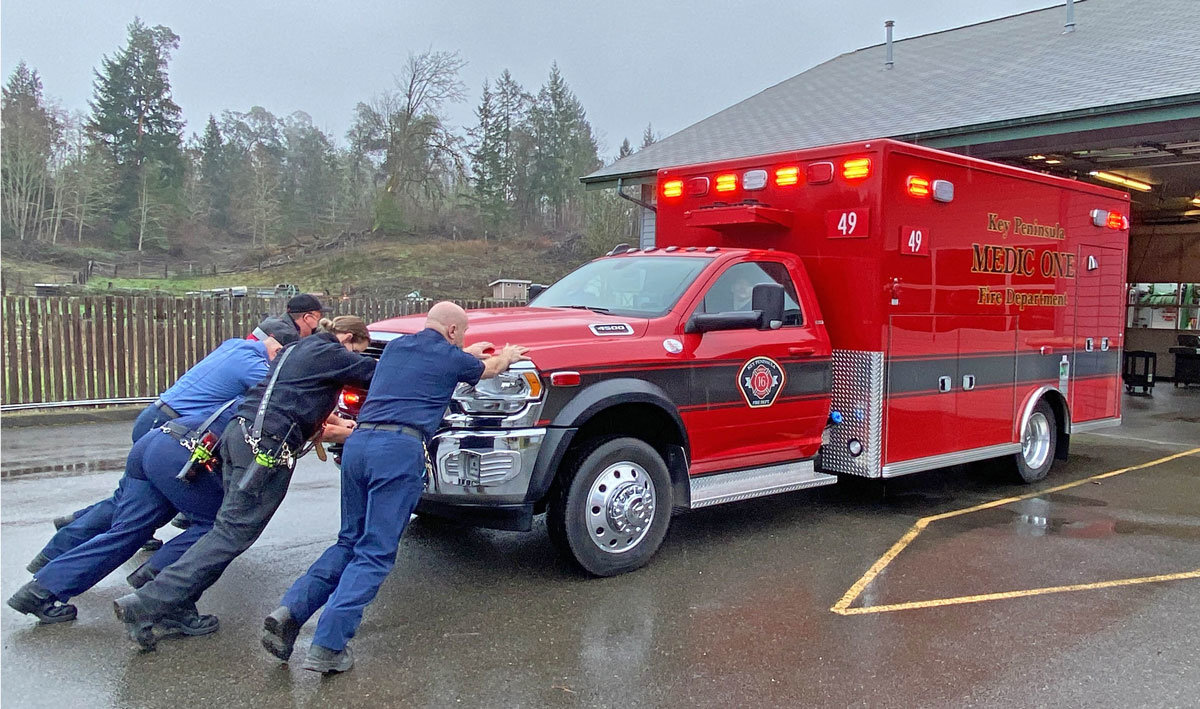 Reenacting a 19th-century tradition, KPFD personnel perform the “push-in” ceremony with a new ambulance at Longbranch station in February. In the 1800s, horses were unharnessed after returning a fire wagon to its station and firefighters pushed it into the bay.